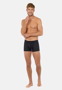 Svarta boxershorts i mjuk tyg, med en åtsittande design, elastiskt midjeband och en formad ficka för stöd.