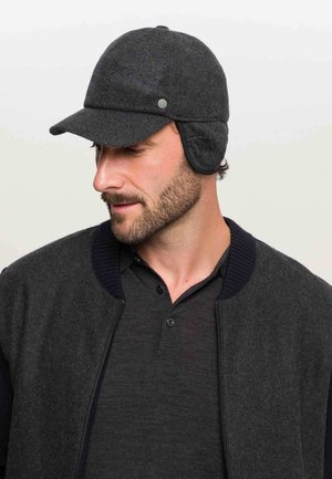 Gray woolen cap with ear flaps, curved brim, and a side button detail. Worn with a dark gray bomber jacket and knit collar.