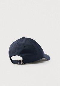 Tmavomodrá šiltovka s oblým šiltom a nastaviteľným pásikom vzadu. Vyrobená z látky s hladkým povrchom a prešitými detailmi.