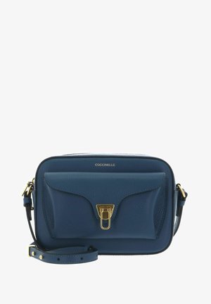 Sac bandoulière compact en cuir bleu avec poche avant, fermoir doré et sangle ajustable, marqué "COCCINELLE" au centre supérieur.