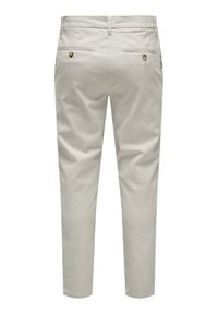 Pantalones de algodón beige con un corte slim, que cuentan con dos bolsillos traseros, costuras sutiles y una textura suave sin patrones o adornos visibles.
