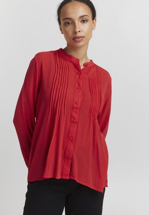 Rode blouse met knopen en een ronde halslijn, met verticale plooien aan de voorkant en lange mouwen. Gemaakt van lichtgewicht stof.