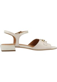 Sandal in pelle beige con un leggero tacco, design con punta aperta, cinturino alla caviglia regolabile e un fiocco decorativo sulla parte anteriore. Texture liscia.
