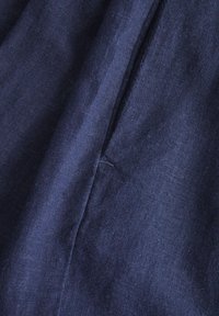 Marineblauwe stof met een licht gestructureerd oppervlak, die een zachte val en subtiele glans vertoont, met zichtbare naaddetails.
