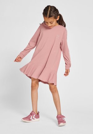 Rosa långärmad klänning med utsvängd fåll och broderade detaljer. Kombinerad med rosa sportiga skor med vita accenter.