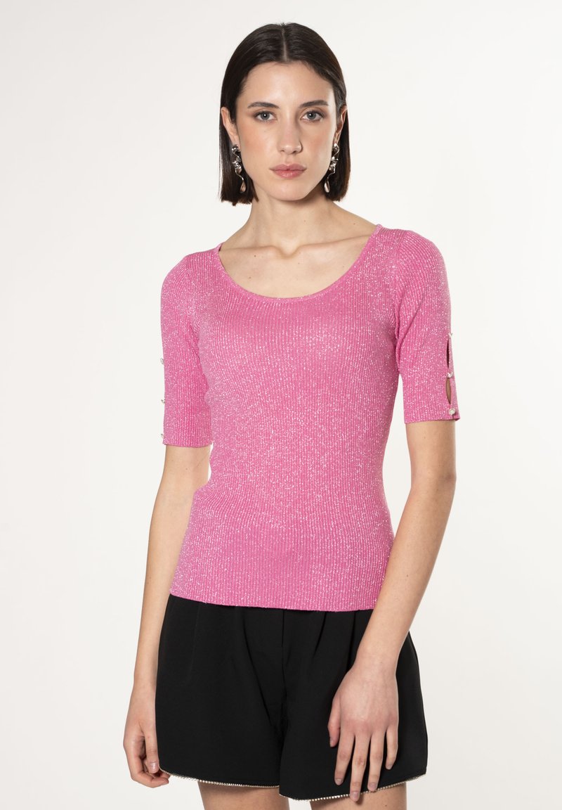 Top corto fucsia fitted con maniche a breve, dal texture a coste e leggero luccichio. Presenta aperture sulle maniche con dettagli a bottoni.