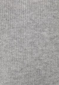 Grau gestrickter Stoff mit einem strukturierten, gerippten Muster. Die Fäden sind eine Mischung aus hell- und dunkelgrau, was eine subtile Farbtiefe erzeugt.