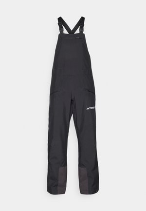 Salopete negre impermeabile cu bretele reglabile, buzunare cu fermoar, picioare inferioare întărite și logo-ul mărcii pe față, concepute pentru activități în aer liber.