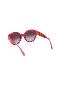 Gafas de sol redondas con un marco brillante de color rosa intenso, lentes oscuros en degradé y brazos delgados rosas con un sutil detalle del logotipo en el lateral.