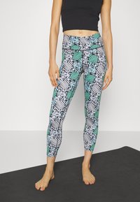 Leggings multicolori con un motivo floreale e a righe in nero, bianco e verde. Realizzati in un materiale flessibile e leggero.