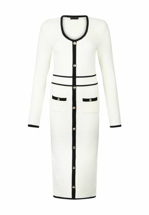 Abito in maglia bianco con bordi neri, scollo a goccia, maniche lunghe e due tasche frontali; presenta bottoni dorati lungo la parte anteriore.