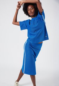 Blue textured knit top with short sleeves, paired with a blue midi skirt featuring a light blue side stripe.