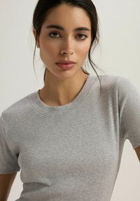 Szara prążkowana koszulka z krótkim rękawem i okrągłym dekoltem, charakteryzująca się miękką fakturą i minimalistycznym designem.