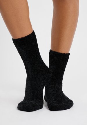 Calzini neri morbidi con una texture soffice, altezza fino al polpaccio e un design a coste. Cuciture della punta lisce e tessuto spesso per il calore.