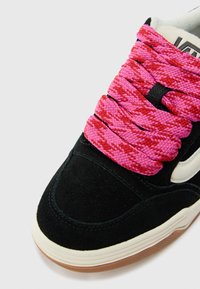 Black suede sneaker featuring thick pink and red patterned laces, white accents on the side, and a gum rubber sole.