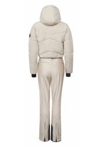 Béžová hřejivá bunda s kapucí, se skládáním z prošívaného materiálu. Připojené, těsné kalhoty se bočními zipy a černými akcenty na koncích nohavic.