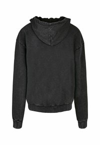 Melnā kapučjaka, kas izgatavota no mīksta auduma, ar aukliņu kapuci, garām piedurknēm un īsu izgriezumu, ar ribotām aprocēm un apakšmalu.