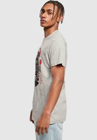 Gray cotton t-shirt featuring a black and red graphic design with a skull motif. Short sleeves and a standard fit.