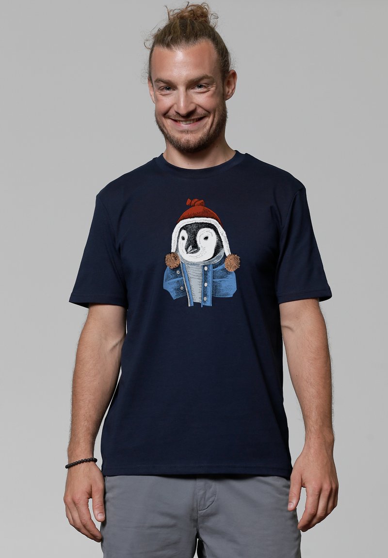 Marineblauwe T-shirt met korte mouwen met een afbeelding van een pinguïn die een rode hoed en een blauwe jas draagt. Van katoen met een zachte textuur.