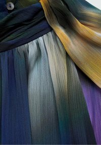 Tissu plissé coloré avec des dégradés de bleu, gris, vert, jaune et violet, doté d'une ceinture à boutons.