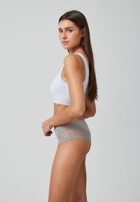 Lichtgrijze naadloze bralette met brede banden, gecombineerd met grijze slips met kantafwerking. Zachte stof met een gladde textuur.