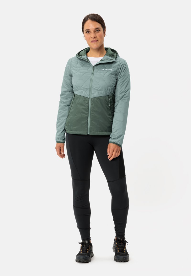 Giacca leggera con cappuccio, con parte superiore trapuntata di colore verde chiaro e parte inferiore di un verde scuro uniforme, dotata di tasche con zip e un design aderente.