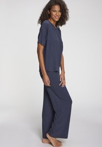 Temno modra komplet za sproščanje iz rebrastega materiala; kratkosleeven top in široke hlače z udobnim krojem in stranskimi šivi.