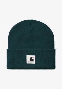 Gorro de punto verde oscuro con puño doblado. Presenta un parche cuadrado blanco con un logo negro. Tela texturizada, diseño ajustado.