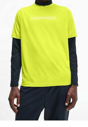 T-shirt performante a maniche corte color giallo neon con logo bianco "CALVIN KLEIN" e maniche lunghe nere sotto. Vestibilità atletica e morbida.