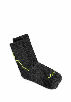 Par de calcetines deportivos gris oscuro con puños acanalados y detalles en zigzag verde neón colocados planos sobre fondo blanco.