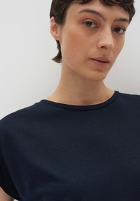 T-shirt girocollo blu navy, realizzata in tessuto morbido, presenta maniche corte e un design semplice senza motivi o accenti visibili.