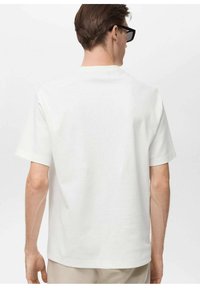 Tricou alb cu mânecă scurtă și guler rotund, având o textură netedă din bumbac. Partea din spate are un design simplu, fără ornamente.