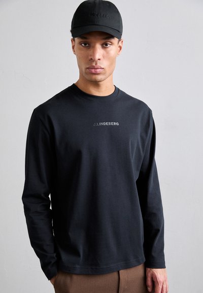 T-shirt noir à manches longues avec un col rond et un petit logo gris sur la poitrine. Associé à une casquette noire assortie.