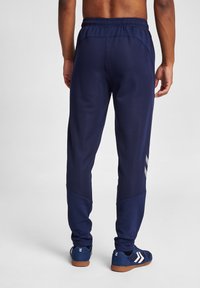 Marineblaue Sporthose mit elastischem Bund, tailliertem Design und netzartiger Textur. Verfügt über weiße Streifenakzente in der Nähe der Knöchel.