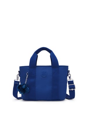 Bolso tote pequeño azul con asas cortas, correa de hombro ajustable y un llavero de mono de peluche colocado en el lado izquierdo.
