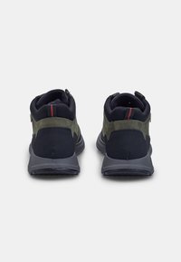 Pantofi sport negri și verzi, cu un upper texturat, guler căptușit și o talpă din cauciuc gri. Prezintă un accent roșu pe toc.