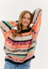 Kolorowy sweter z dzianiny z oversize'owymi rękawami, w paski w odcieniach brzoskwini, czerni i kremu, o teksturowanym, puszystym wykończeniu.