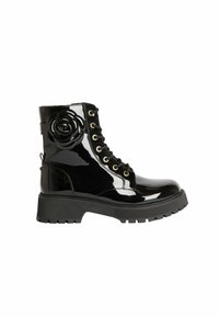 Botas de combate de charol negro con un acabado de alto brillo, cordones frontales, ojales dorados y un acento floral en el lado. Suela gruesa con relieve.