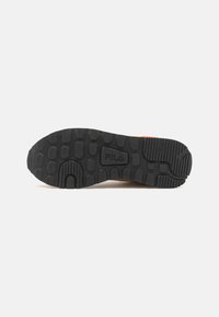 Black rubber sneaker sole with textured traction pattern. The brand "FILA" is embossed on the side, featuring grooves and circular knobs.