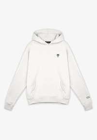 Vit hoodie i mjukt tyg, har en framficka, svart palmträd-logotyp på bröstet och text på ärmslutet.