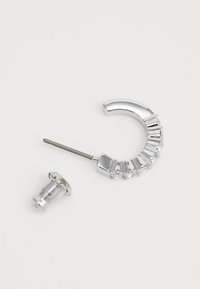 Orecchino a cerchio in argento con un design curvo accentuato da strass rettangolari e rotondi. Chiusura con un perno e un retro metallici.