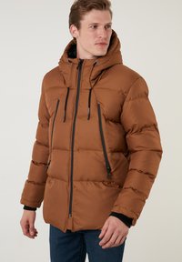 Brun polstret jakke med hætte, der har sorte detaljer og lynlåse. Materialet ser glat ud, med et quiltet design og høj krave.