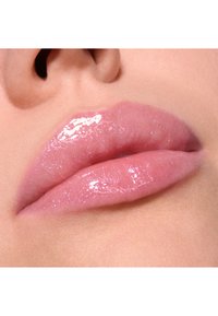 Lucida lucida rosa con una finitura scintillante, che mette in risalto labbra lisce e piene con una consistenza morbida. Il colore è pallido con un leggero luccichio.