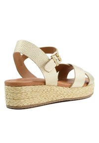 Sandale compensée en toile beige avec des brides en simili cuir texturé, une fermeture à boucle et une plateforme en jute tressé. Dessous lisse.