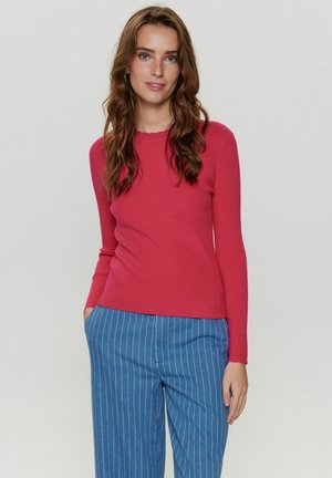 Maglione a maniche lunghe a coste di un vivace colore rosa, con un collo scallop, abbinato a pantaloni a righe blu.