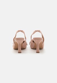 Lyse rosa suede høyhælte sko med åpen bak, med en rund tå og en slank blokkhæl. Designet inkluderer en forsiktig samlet stropp.