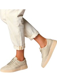 Beige lærersandaler med teksturert overflate, flate snørebånd og en kraftig gummi såle. Kombinert med rullet hvit denimbukse.
