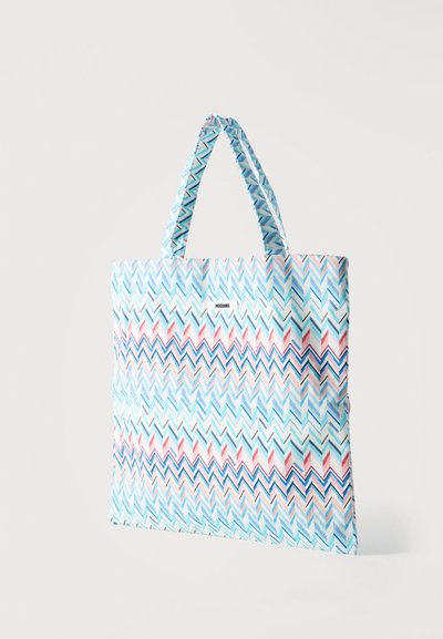 Τσάντα tote με μοτίβο ζιγκ-ζαγκ σε απαλό μπλε, ροζ και λευκό χρώμα και κοντές λαβές σε λευκό φόντο.