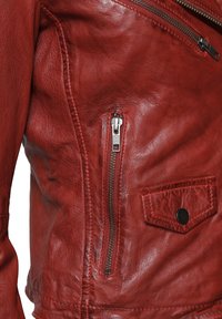 Rote Lederjacke mit strukturierter Oberfläche, asymmetrischem Reißverschluss und einer aufgesetzten Tasche mit Druckknopf. Mit silbernen Beschlägen akzentuiert.