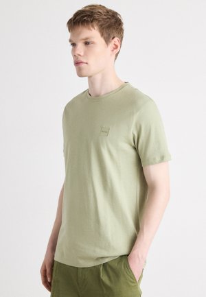 Helle grüne Baumwoll-T-Shirt mit kurzen Ärmeln, Rundhalsausschnitt und einem kleinen quadratischen Logo auf der Brust. Weicher Stoff, lässige Passform.
